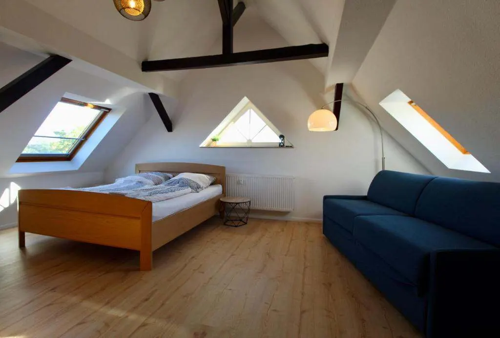 Wohn- und Schlafraum unterm Dach mit Doppelbett und Schlafsofa